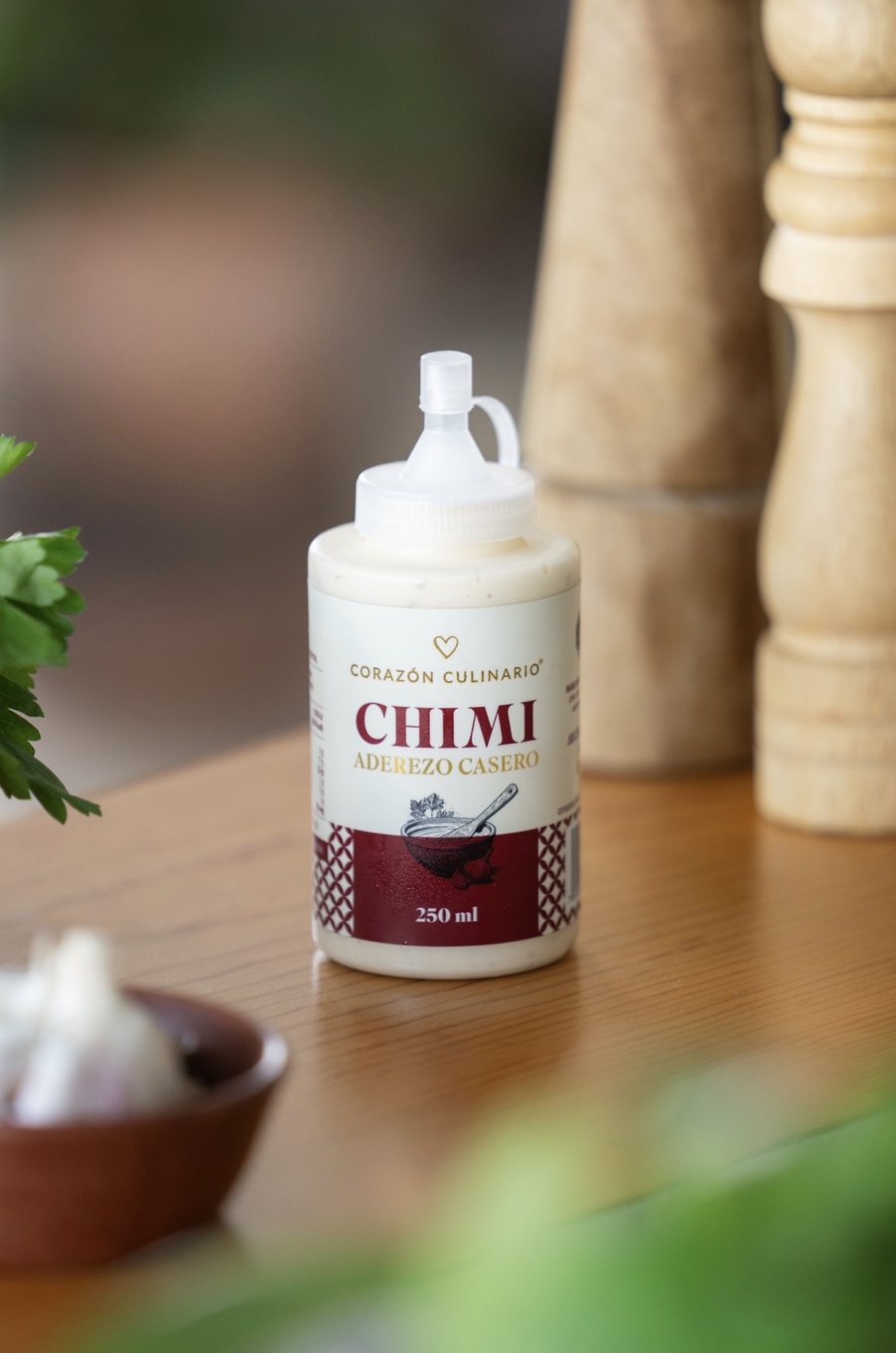 Frasco de Chimi, aderezo casero de Corazón Culinario, sobre una mesa de madera