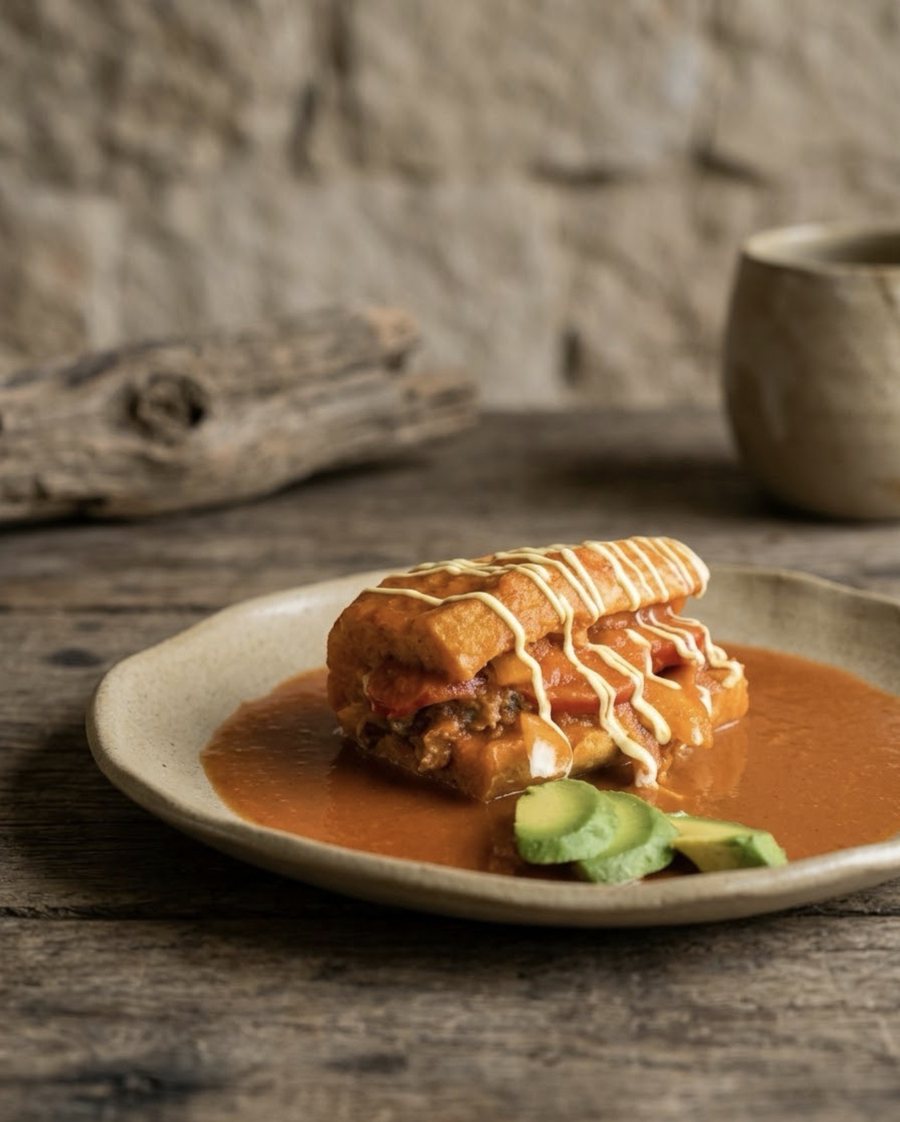 Lonche bañado en salsa roja con aguacate